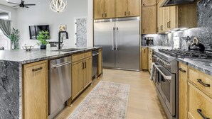 A modern kitchen with wooden cabinets, stainless steel appliances, and a marble countertop. - Waterfront Canyon Lake Getaway w/ Lakeshore Park (Canyon Lake)