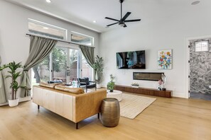 Ein modernes Wohnzimmer mit Ledersofa, Fernseher und Deckenventilator.