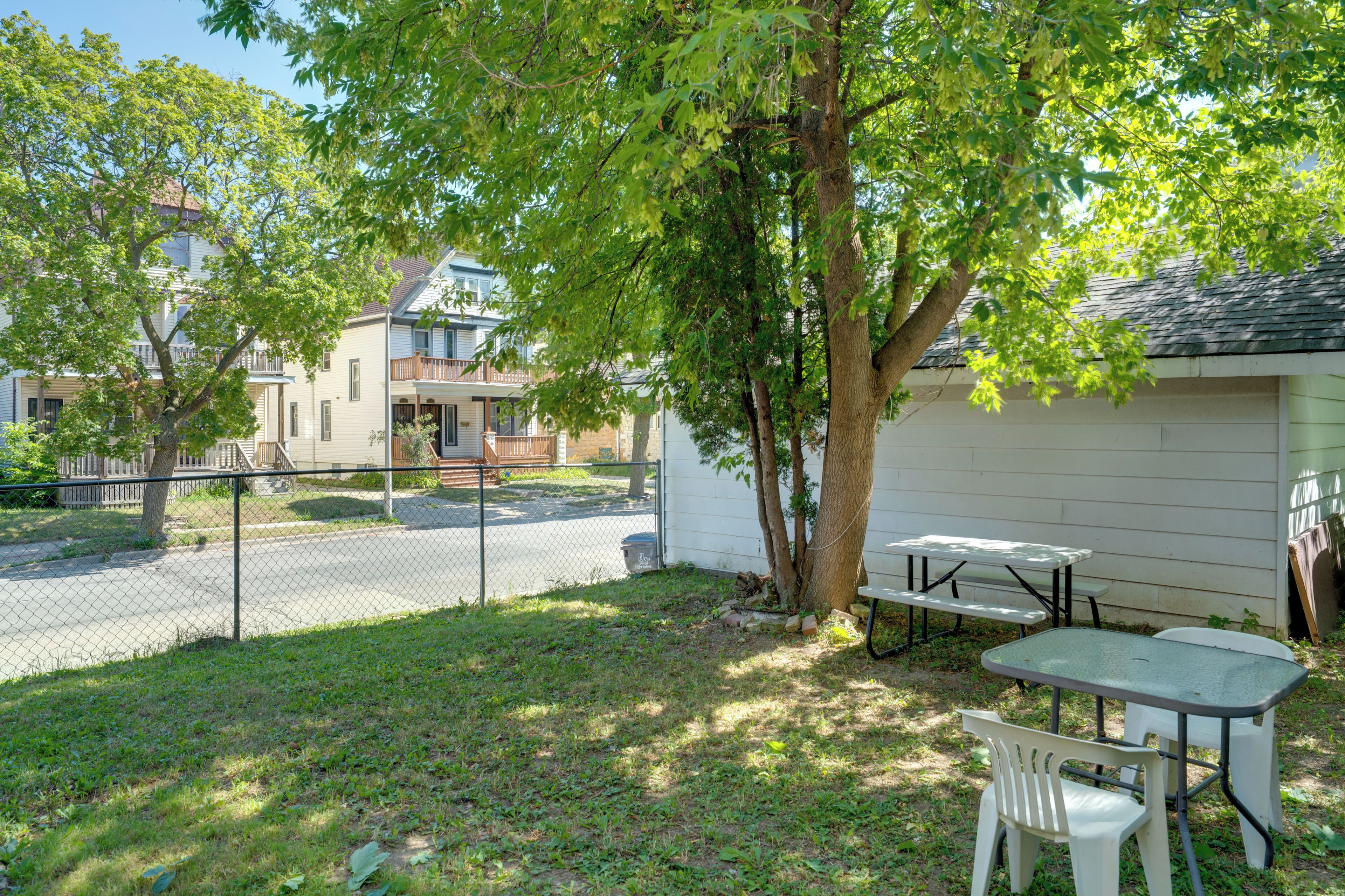 A residential area with a fenced yard, a picnic table, and a building with a balcony.