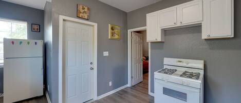 A kitchen with white cabinets, a refrigerator, and a stove.