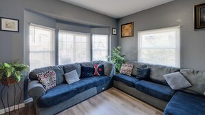 A living room with a sectional sofa, large windows, and a plant. - Fenced Yard! Spacious Home, 4 Mi to Dtwn Milwaukee (Milwaukee)