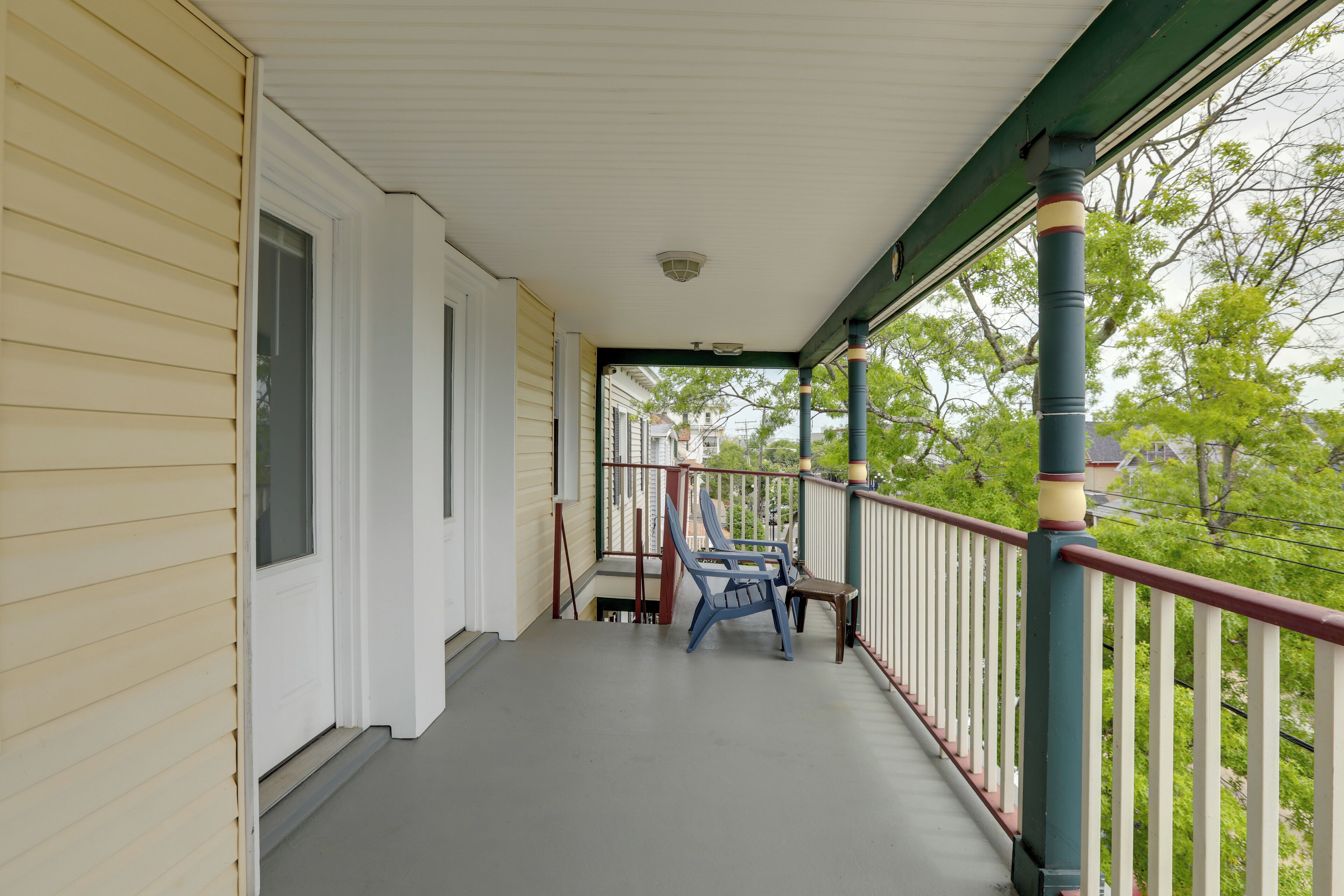 Une véranda couverte avec une balustrade, un banc et une porte.