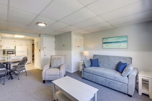 A living room with a grey sofa, a white coffee table, a grey armchair, and a dining area with a table and chairs. - Walk to Beach, Boardwalk, Restaurants: Asbury Park (Ocean Grove)