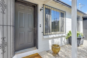 A house with a dark gray door, white siding, and a window with decorative metal bars. - Tucson Home Base Near I-10, 5 Mi to Downtown! (Tucson)