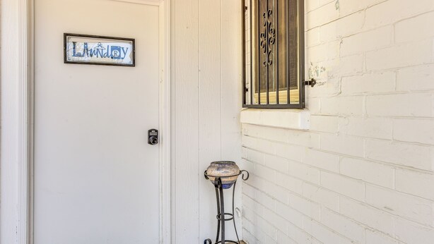 A white door with a sign that reads 'Laundry' and a metal gate on a white brick wall. - Tucson Home Base Near I-10, 5 Mi to Downtown! (Tucson)