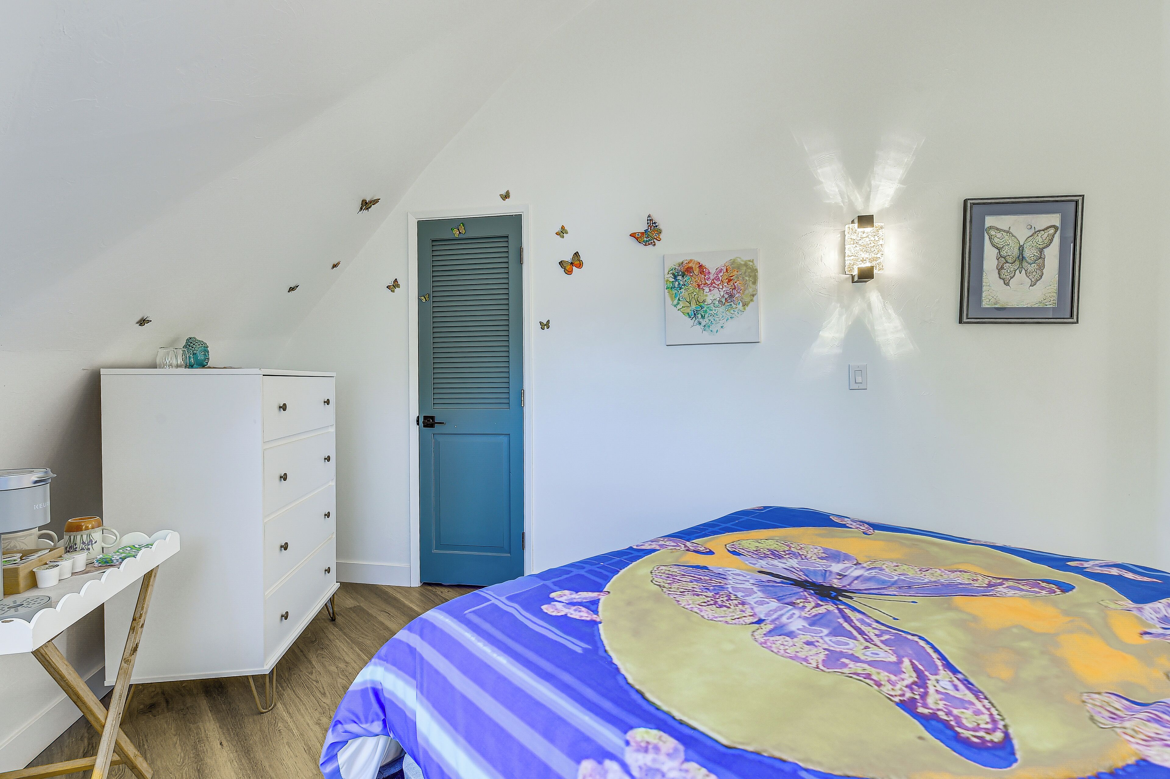 A bedroom with a bed, dresser, and a door.
