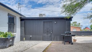 Un garage avec une porte noire, un barbecue et un pot de fleurs.
