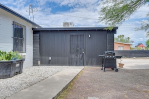 Eine Garage mit einer schwarzen Tür, einem Grill und einem Blumentopf.