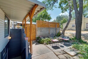 Ein überdachter Patio-Bereich mit Holzzaun, eine Sitzecke mit gepolstertem Stuhl und ein Kiesweg.