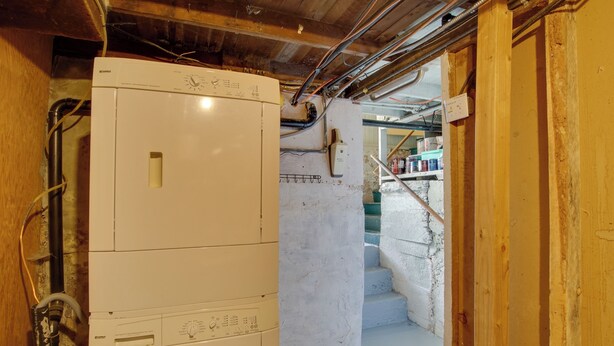 A laundry room with a washing machine and dryer, a staircase leading to a second floor, and exposed electrical wiring. - Walk to SSU & Shakespeare Fest! Colorful Retreat (Cedar City)