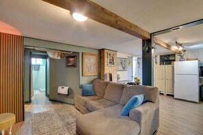 A living room with a sofa, a wooden ceiling beam, a kitchen area with cabinets, and a refrigerator. - Walk to SSU & Shakespeare Fest! Colorful Retreat (Cedar City)