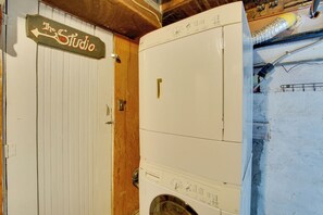 Ein Waschraum mit einer weißen Waschmaschine, einer Holztür und einem Schild mit der Aufschrift 'The Studio'.