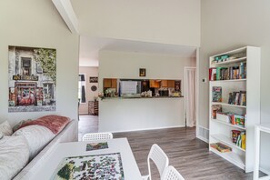Un soggiorno con un divano, un tavolino con un puzzle, una libreria e una cucina sullo sfondo.