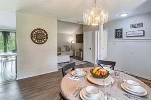 A dining area with a round table set for four, a chandelier, and a wall with decorative items. - Great for Families! Schertz Getaway 6 Mi to Zoo (Cibolo)