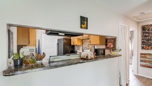 A kitchen with a marble countertop, wooden cabinets, and a view into the adjacent dining area. - Great for Families! Schertz Getaway 6 Mi to Zoo (Cibolo)