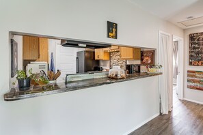 A kitchen with a marble countertop, wooden cabinets, and a view into the adjacent dining area. - Great for Families! Schertz Getaway 6 Mi to Zoo (Cibolo)