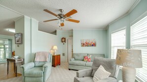 Ein Wohnzimmer mit Deckenventilator, zwei Sofas, einem Tisch mit Lampe und einem Bild an der Wand.