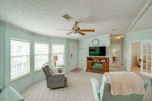 A living room with a ceiling fan, a television, a fireplace, and a sofa. - Active-adult Community! Port Charlotte Home, Lanai (Punta Gorda)