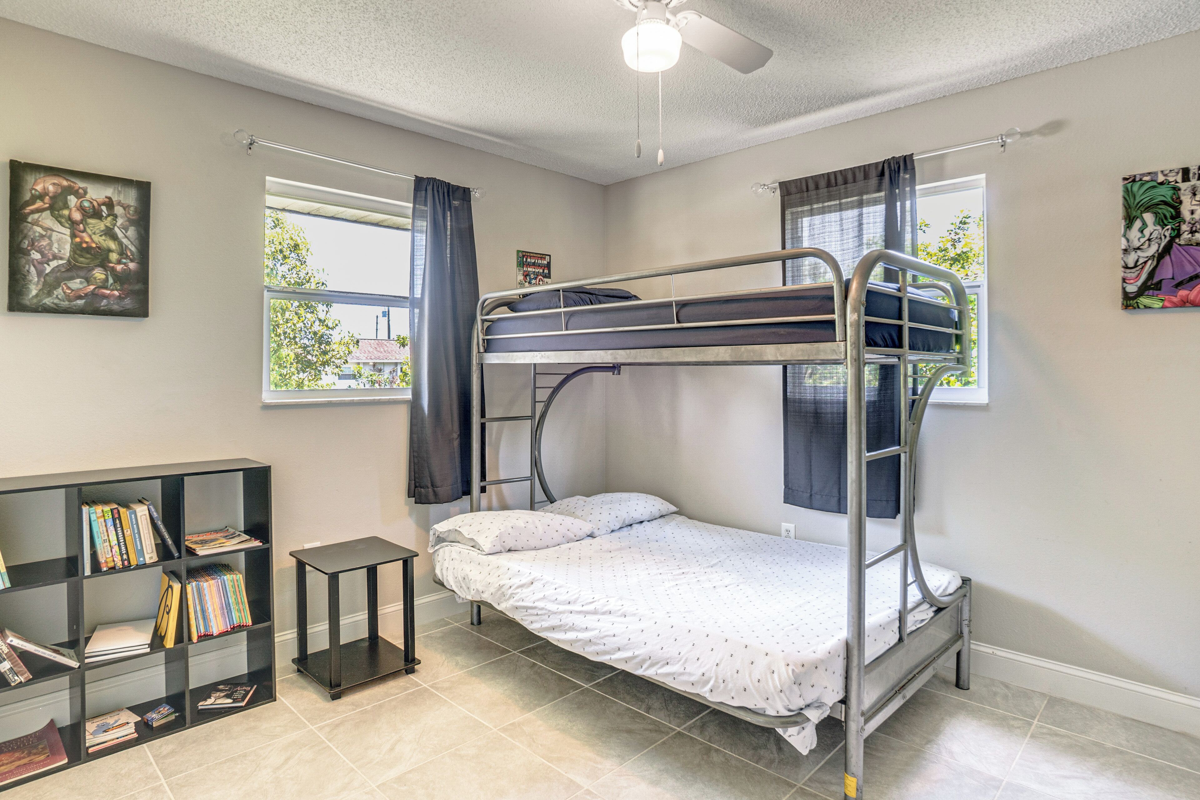 Une chambre avec un lit superposé, une bibliothèque et un ventilateur de plafond.