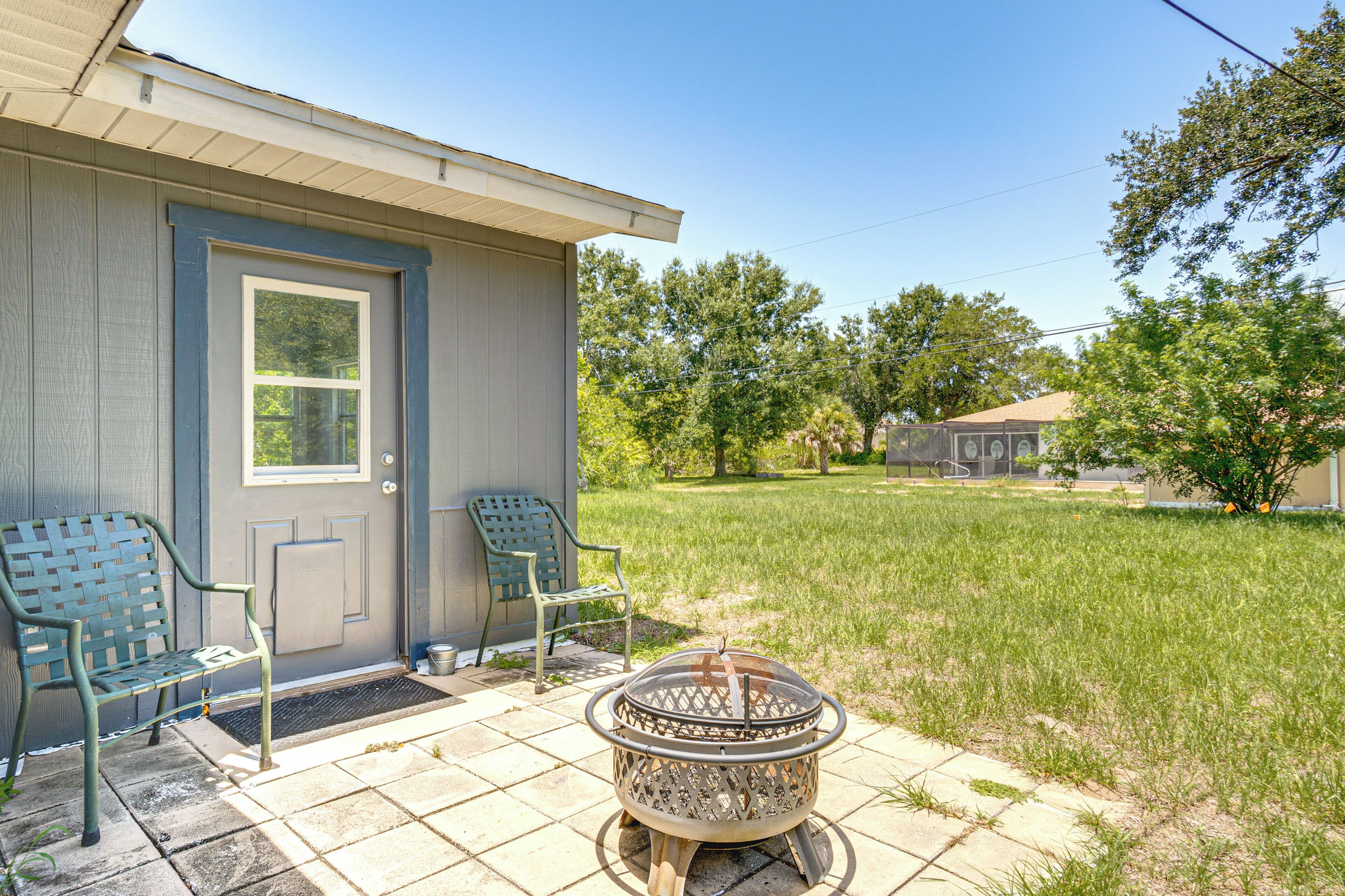 A house with a front door, two chairs, a fire pit, and a lawn.
