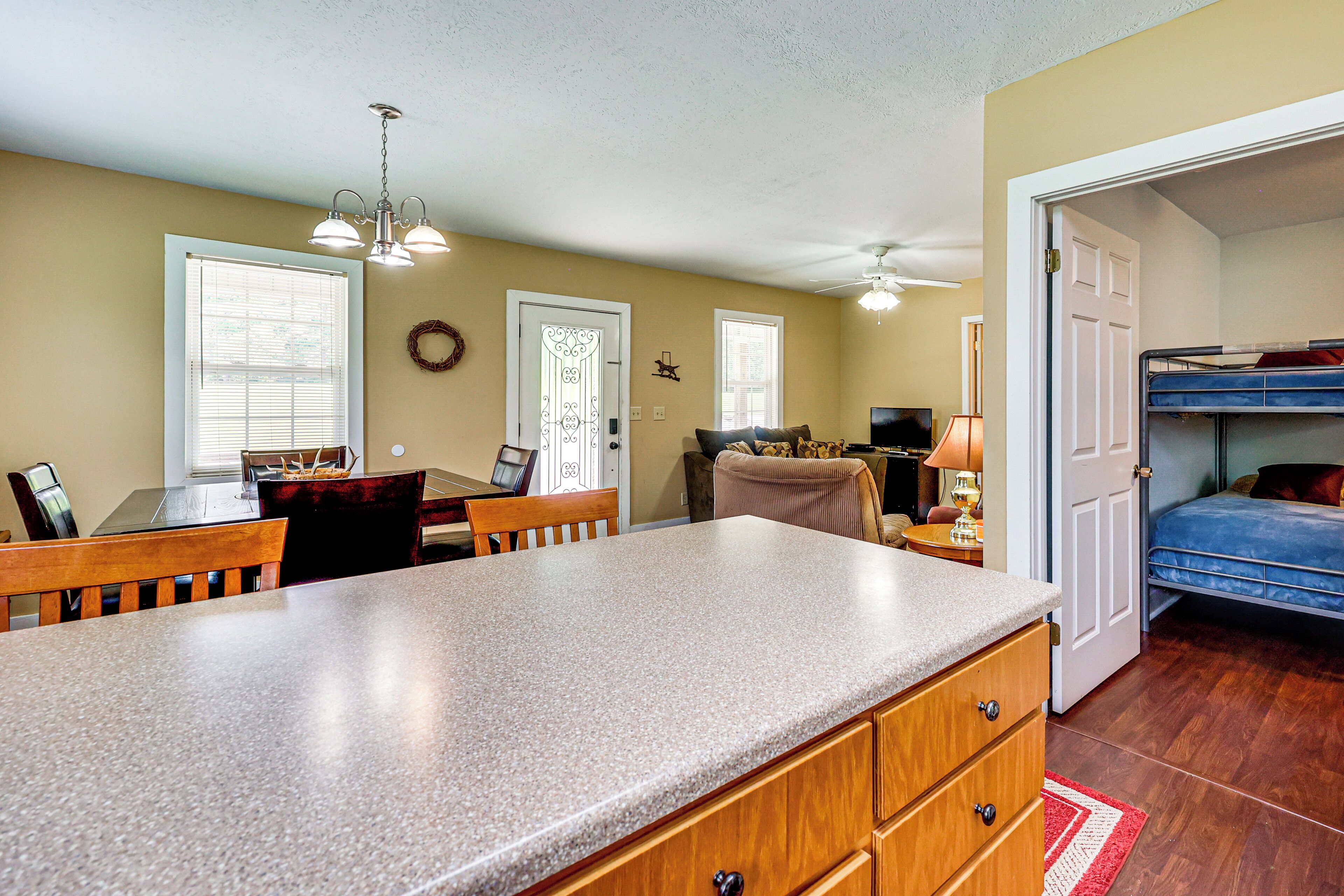 A compact living space with a kitchen area, dining table, and a bunk bed.