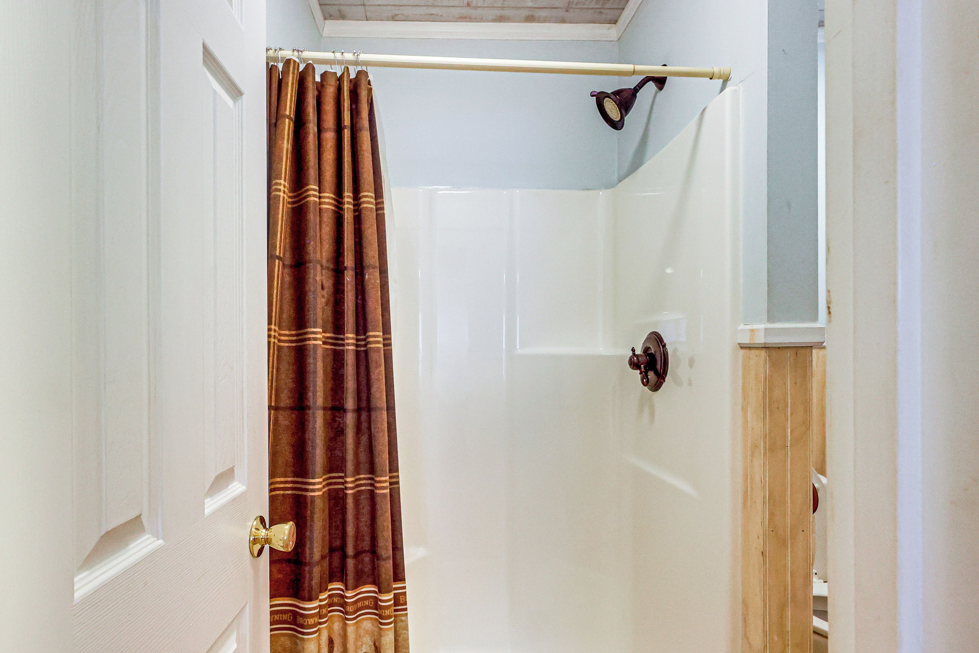 A shower with a brown curtain, a white door, and a wooden door frame.