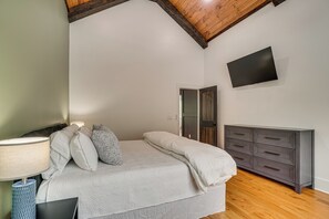 Ein Schlafzimmer mit Bett, Nachttischlampe, Kommode, Fernseher und einer Tür.