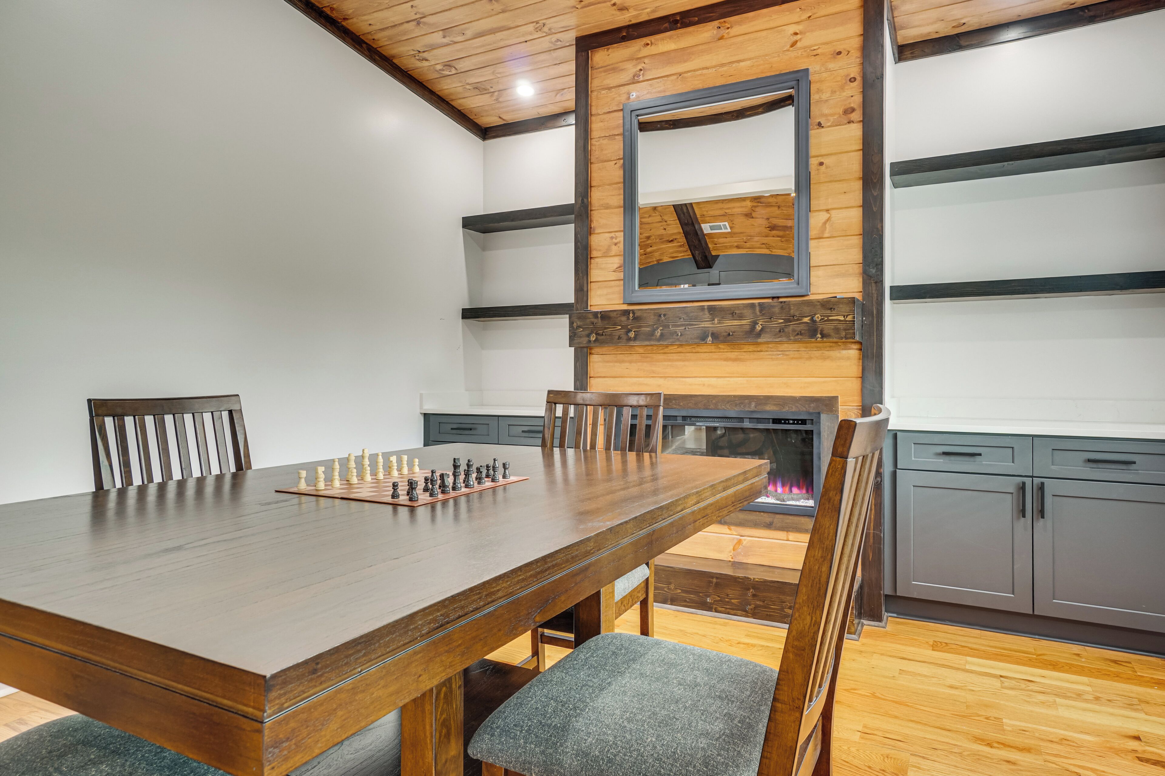 A dining area with a wooden table, chairs, and a chessboard.