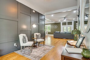 Ein modernes Wohnzimmer mit einem grauen Sofa, zwei Sesseln, einem Holztisch und einem dekorativen Spiegel.