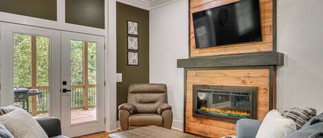 A living room with a fireplace, a television mounted above it, and a comfortable seating area with a sofa and a chair.