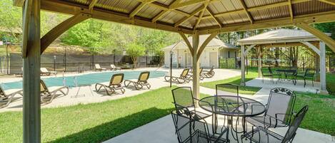 A covered outdoor area with a pool, lounge chairs, and a table with chairs.