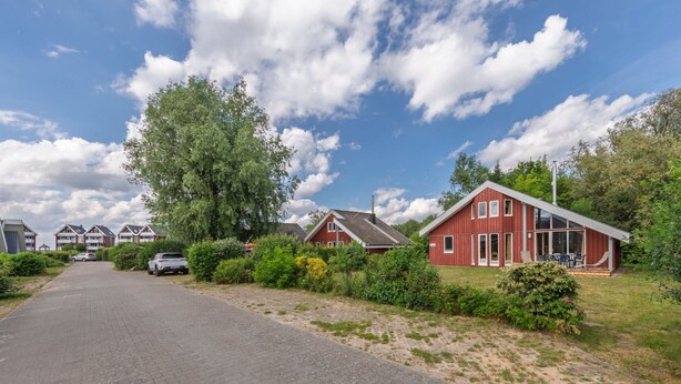 A residential street with houses, a paved road, and a clear sky. - Gemutliches Ferienhaus mit Garten und Terrasse im Hafendorf Muritz (Rechlin)