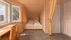 A wooden cabin room with a bed, a window, and a door. - Gemutliches Ferienhaus mit Garten und Terrasse im Hafendorf Muritz (Rechlin)