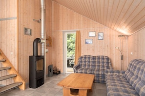 Ein Holzinnenraum mit Kamin, einer Couch, einem Tisch und einer Treppe.