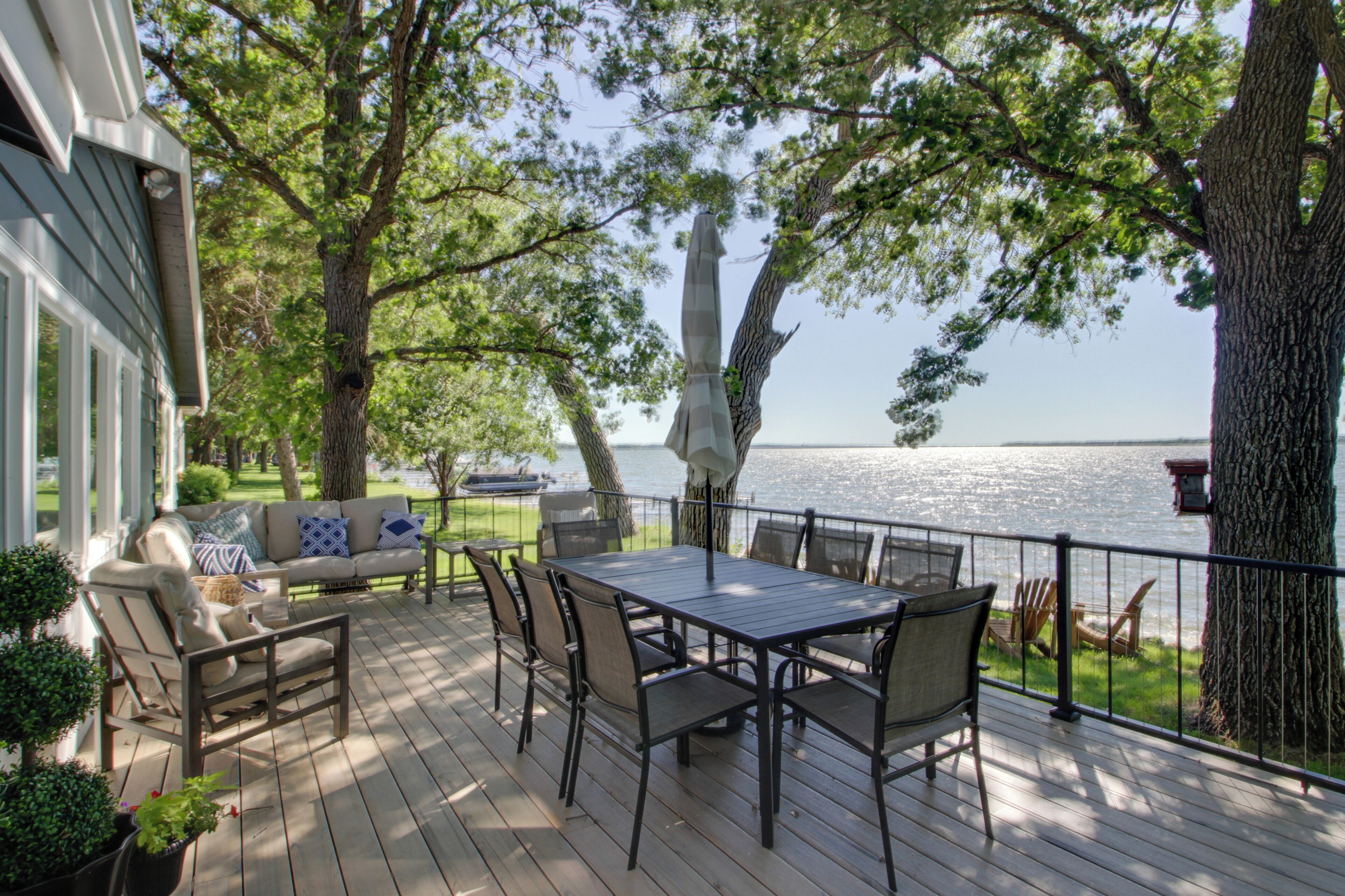 A deck with a table and chairs, overlooking a body of water.