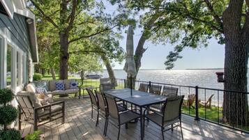 A deck with a table and chairs, overlooking a body of water.