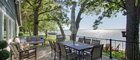A deck with a table and chairs, overlooking a body of water.