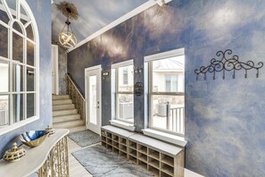 A hallway with a blue wall, a wooden bench, a staircase, and a decorative ceiling light.