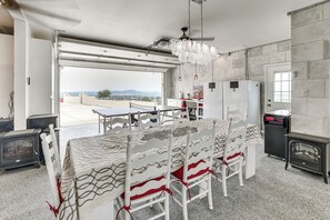 A modern kitchen with a dining area, a view through the open garage door, and a stone wall.