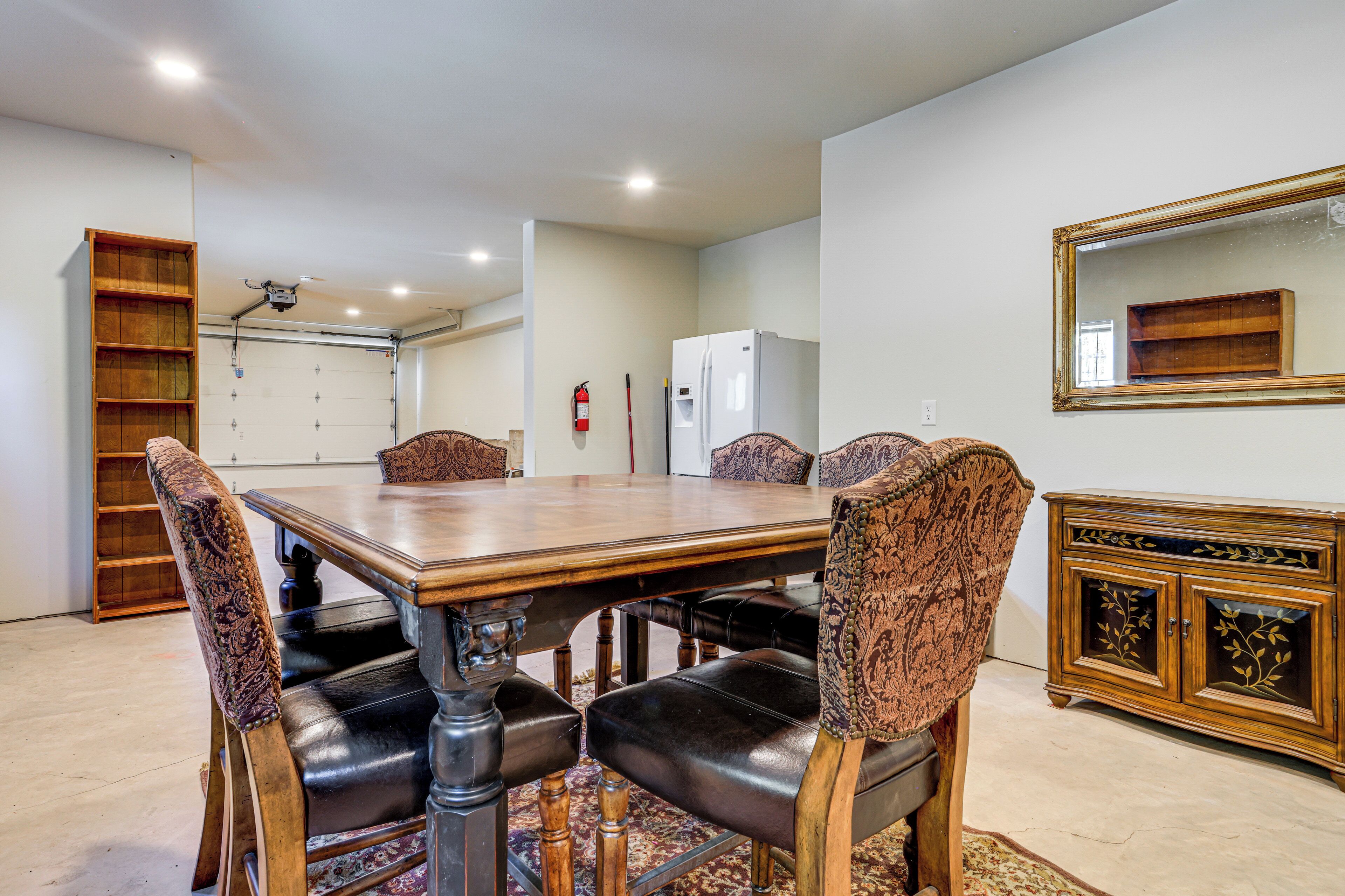 A dining area with a wooden table, leather chairs, a bookshelf, and a refrigerator.