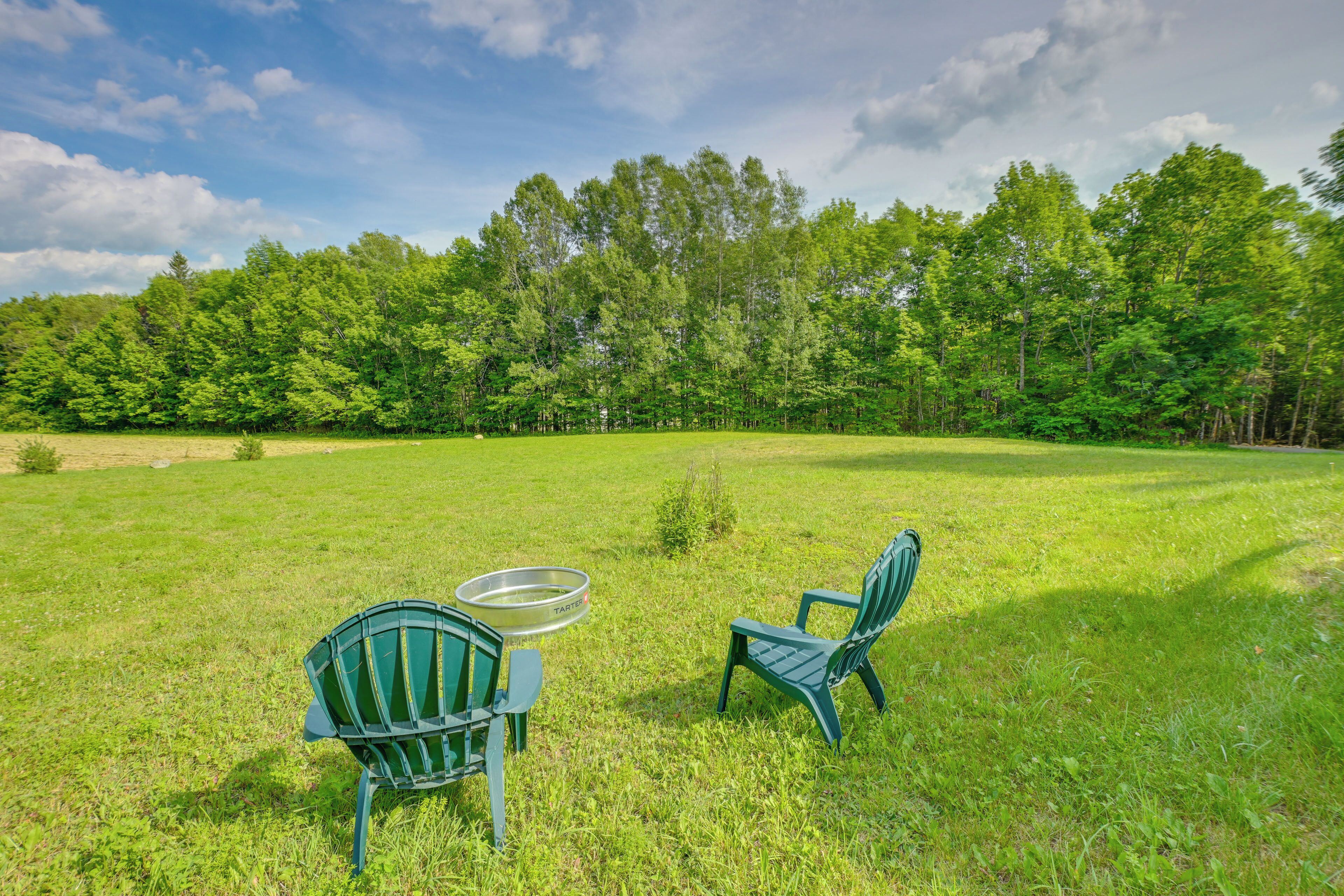 A grassy field with two green chairs and a metal table.