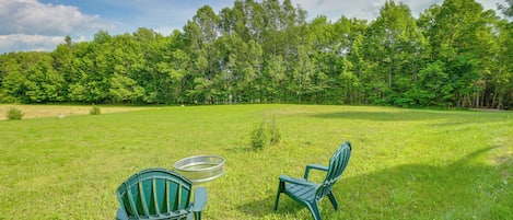 A grassy field with two green chairs and a metal table.