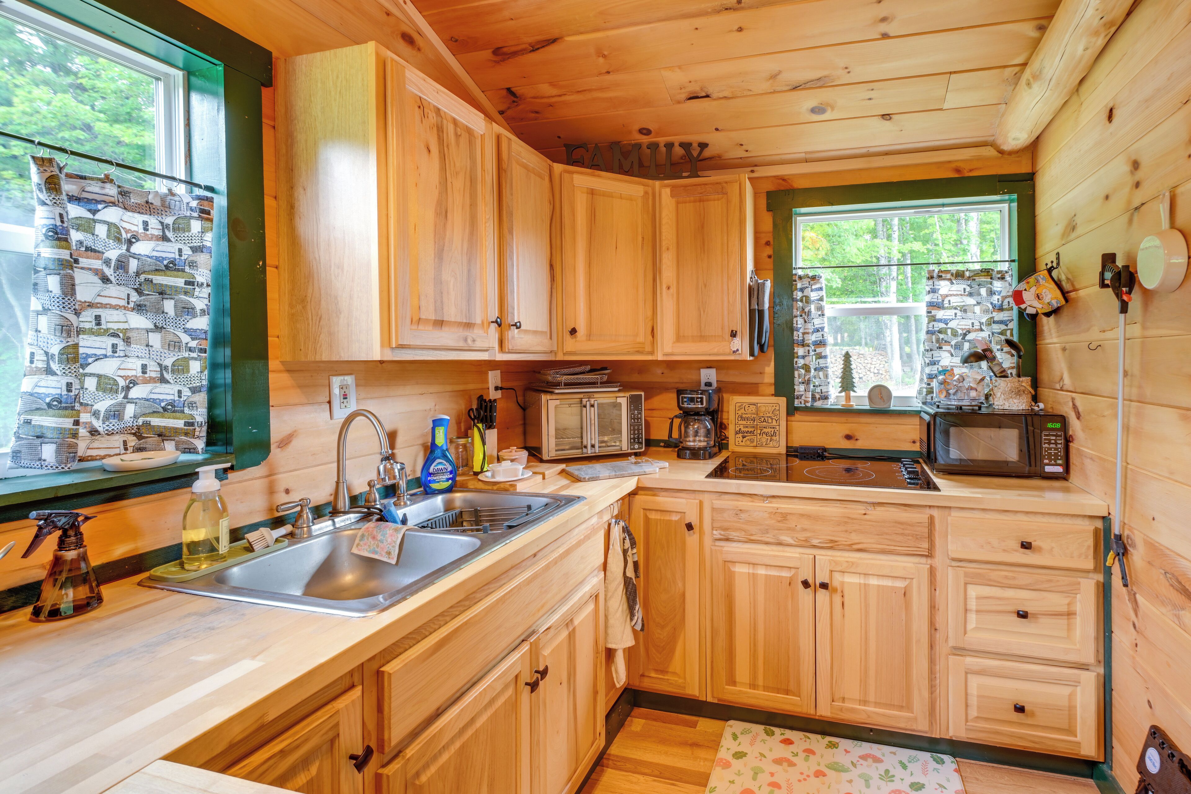 A wooden cabin kitchen with a sink, microwave, and cabinets.
