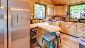 A kitchen with wooden cabinets, a stainless steel refrigerator, a wooden countertop, and a window with a view of trees. - Ride-in/ride-out North Woods Cabin: On-site Trails (Lee)