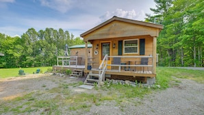 A wooden cabin with a porch, outdoor seating, and a small staircase leading to the entrance. - Ride-in/ride-out North Woods Cabin: On-site Trails (Lee)