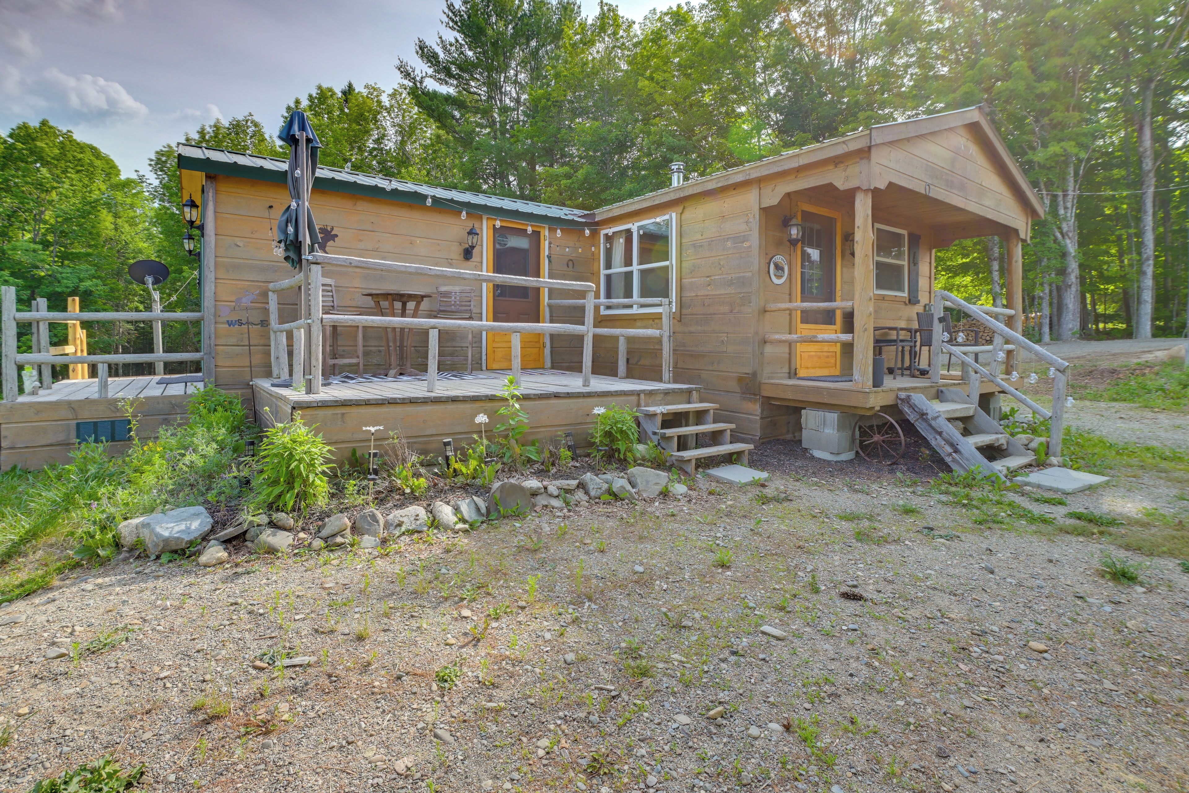 A wooden cabin with a porch, a small deck, and a stone pathway leading to the entrance.