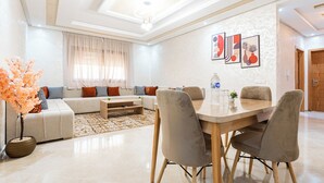 Un salon moderne comprenant un ensemble de canapés, une table à manger avec des chaises, une table basse et une grande fenêtre avec des rideaux.