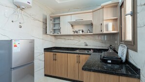Une cuisine moderne dotée de plans de travail en marbre, de meubles en bois, d’un réfrigérateur en acier inoxydable et d’un four encastré.