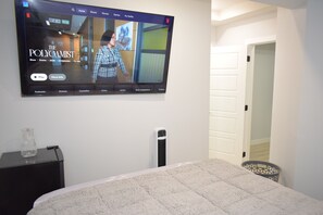 A television mounted on a wall displaying a show titled 'The Polycamist.' - Luxury Studio Room (Edmonton)