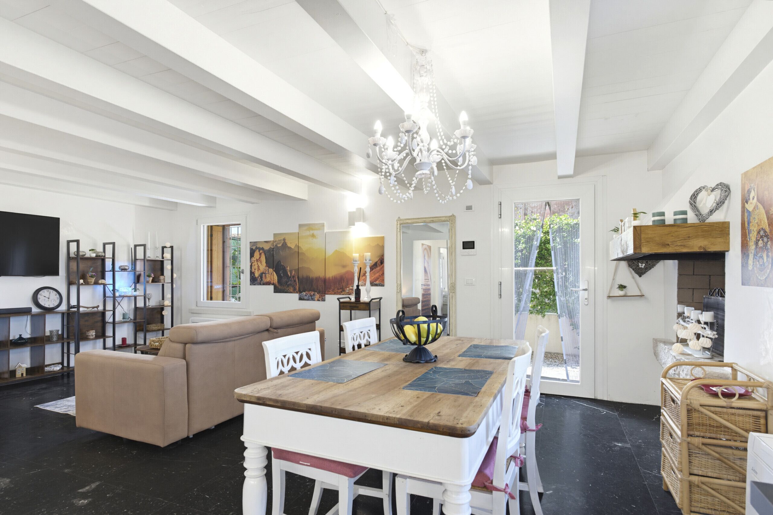 A spacious living area with a wooden dining table, a sofa, and a chandelier.